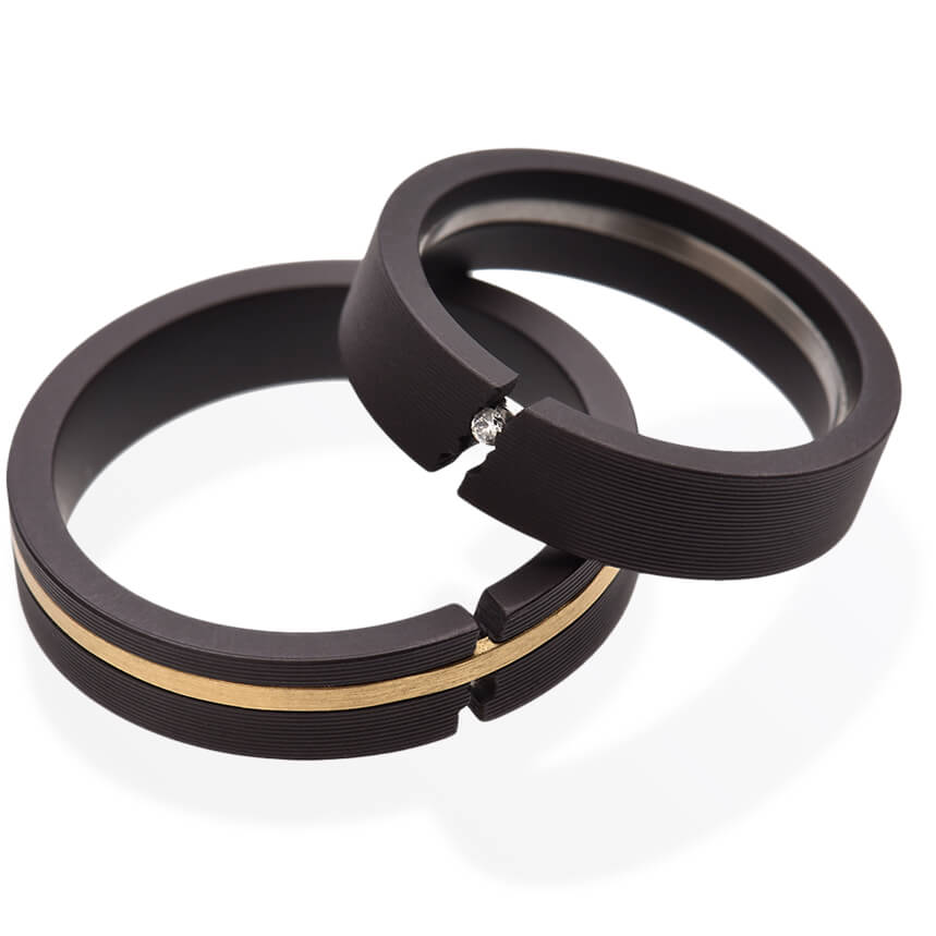 'Ur-Sprung' ist ein besonderer Trauring, mit ausgefallenem Design. Der linke Ring ist aus PVD-beschichtetem Edelstahl, sowie 750er Gelbgold gefertigt der rechte Ring weist einen Brillanten auf und ist ebenfalls aus PVD-beschichtetem Edelstahl hergestellt.